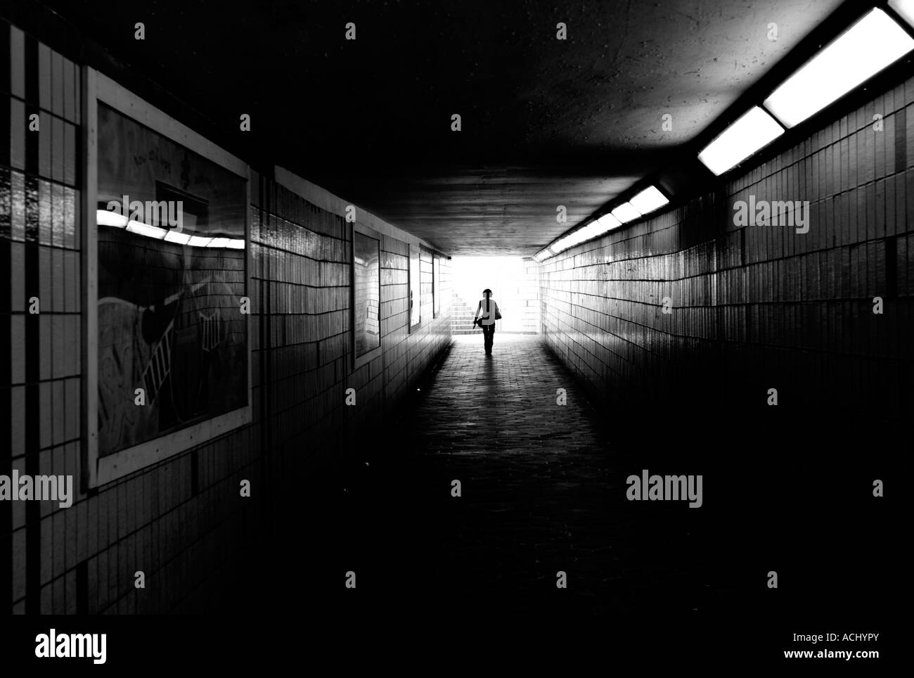 Femme de marcher seul dans le passage souterrain du métro - la lumière au bout du tunnel noir et blanc (monochrome) - de derrière Banque D'Images