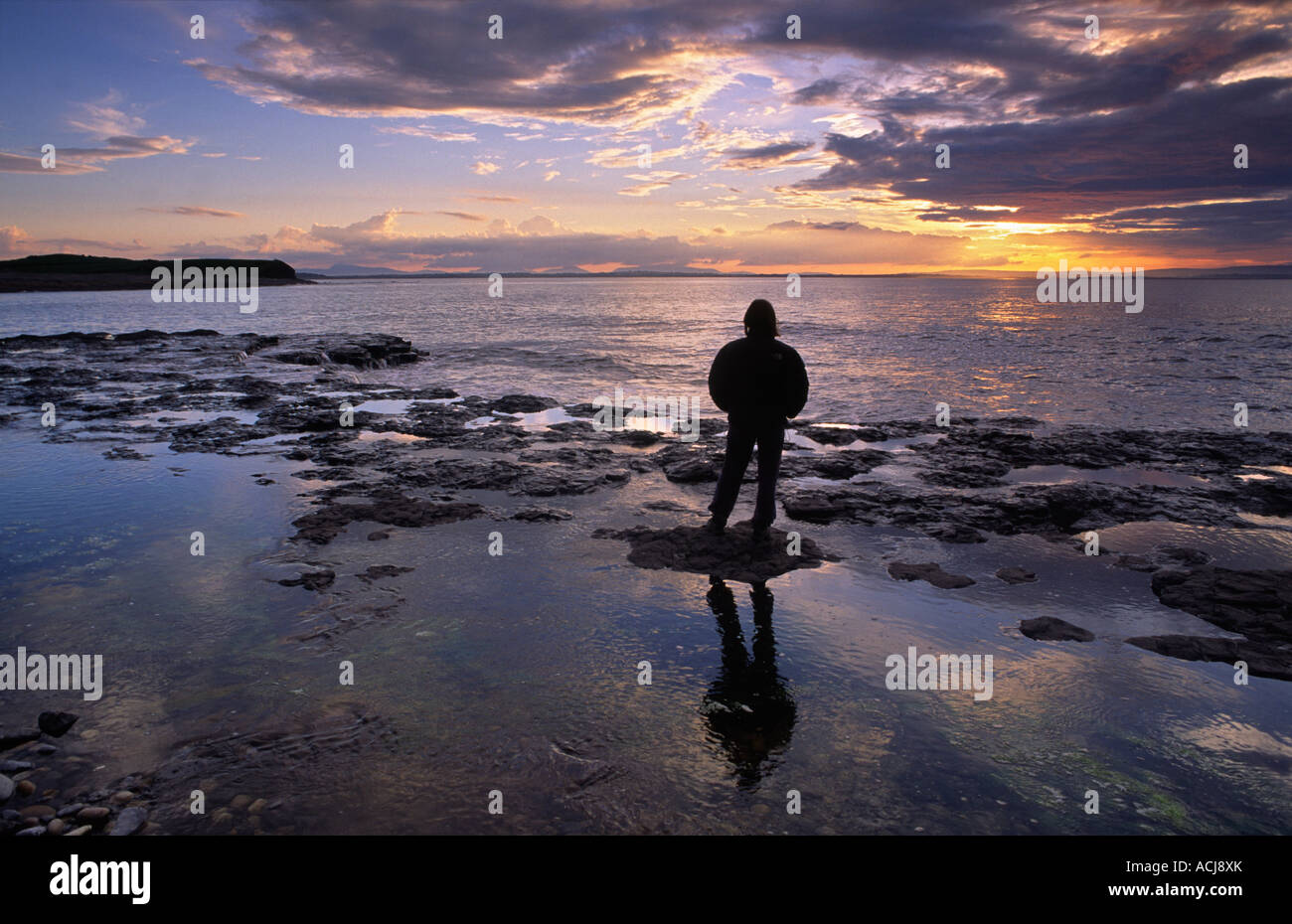 Personne à regarder le coucher du soleil à partir de la rive de la baie de Killala, Sligo, Irlande. Banque D'Images