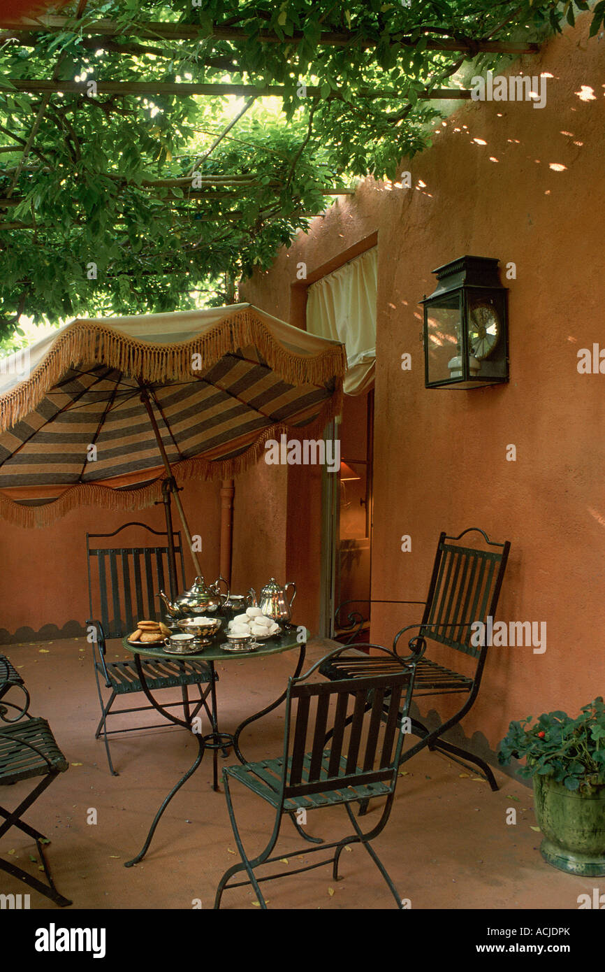 Terrasse d'une maison fauteuil et table en fer de murs orange parasol vert Banque D'Images