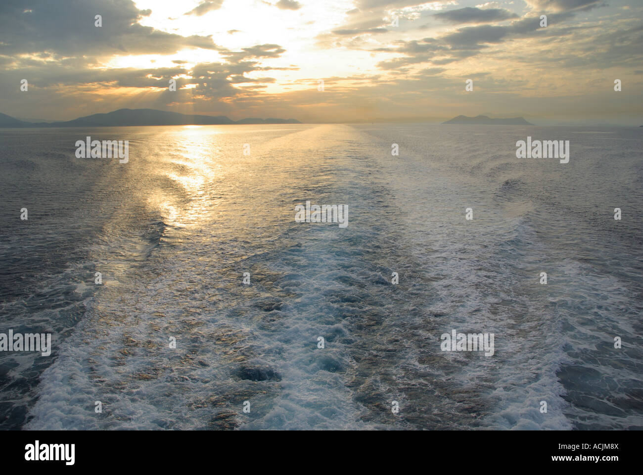 La turbulence de l'eau d'hélice de bateaux service en mer Égée et le coucher du soleil au dessus de l'horizon des côtes de Grèce vu à partir de la poupe du bateau de croisière au départ de mainland Banque D'Images