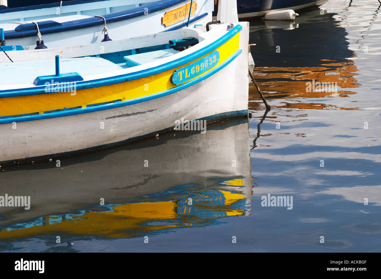 Les bateaux de pêche typiques provençales peints dans des couleurs blanc, bleu, vert rouge jaune, amarré au keyside, réflexions Sanary Var Cote d'Azur France Banque D'Images