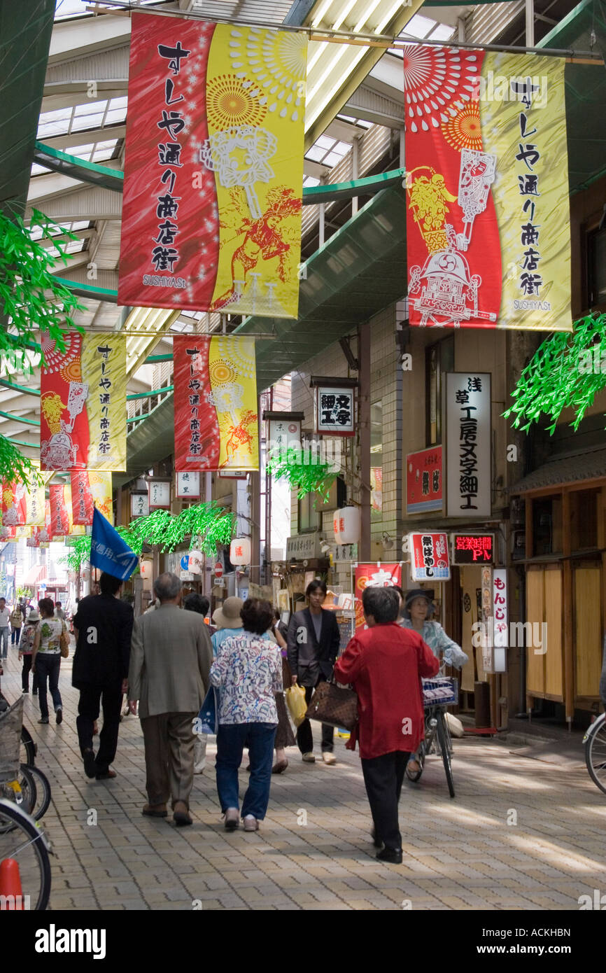 Les gens marcher dans un centre commercial couvert occupé avec des bannières colorées dans la zone touristique d'Asakusa Tokyo Japon Banque D'Images