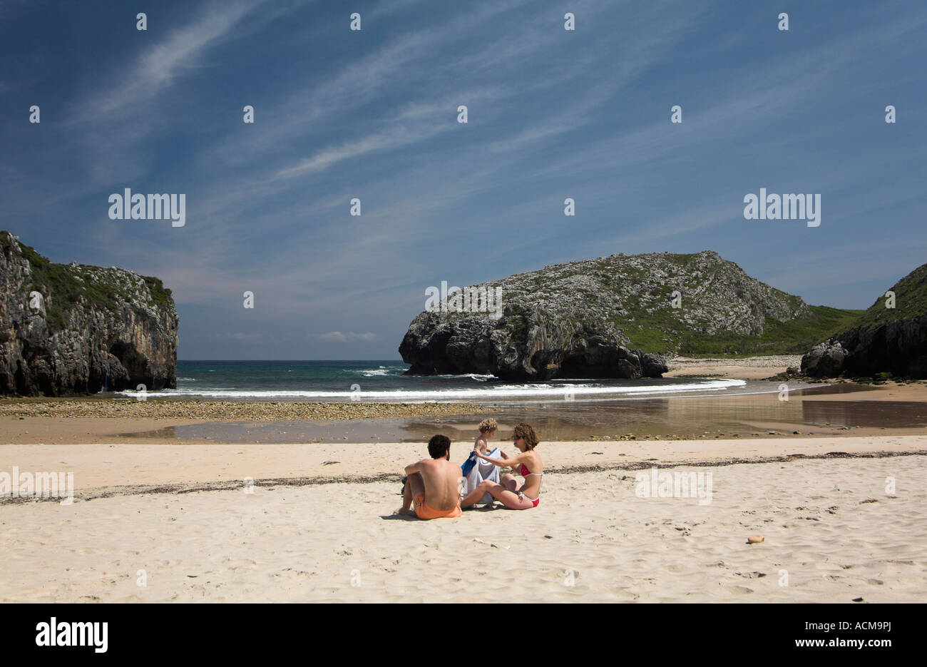 Homme Femme avec un jeune enfant bébé enfant assis assis plage de Cuevas del Mar principidad de Asturias Espagne Costa Verde Banque D'Images
