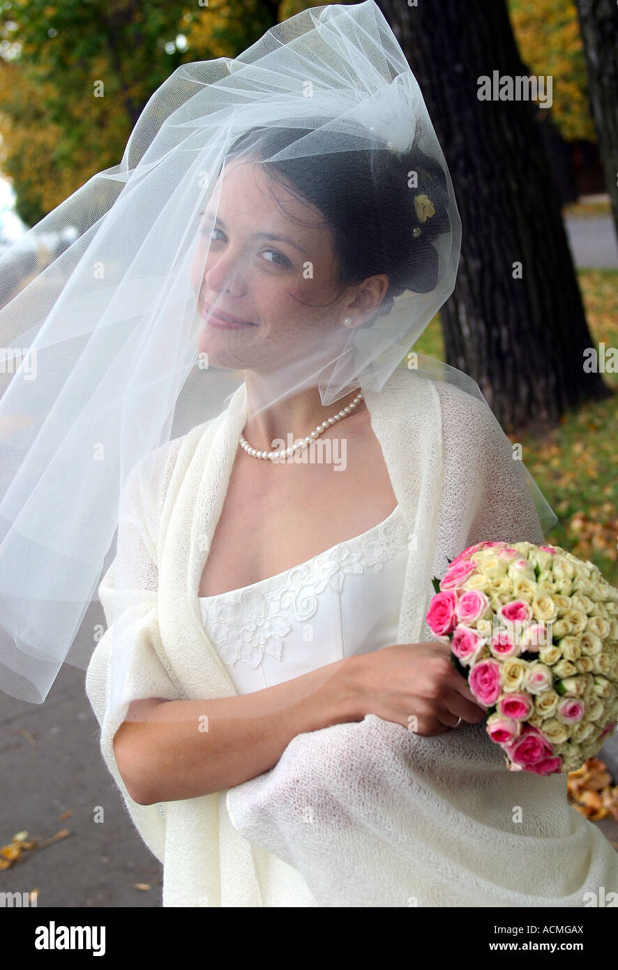 Portrait d'une jeune mariée avec un voile, souffle sur son visage. Elle tient un bouquet de fleurs. Banque D'Images