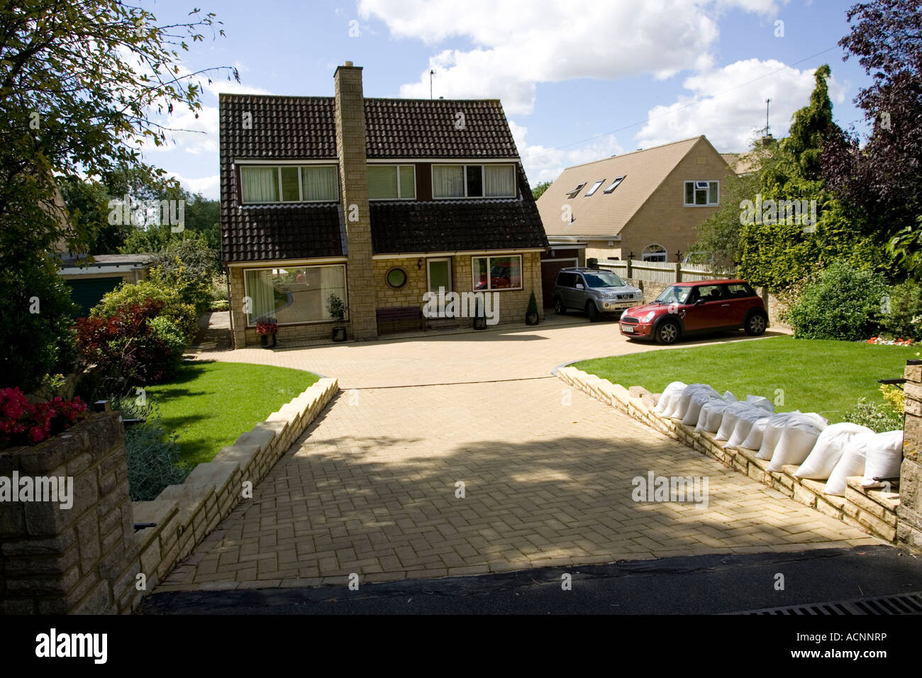 Maisons d'habitation avec de grandes zones de façade pavés causant des eaux de ruissellement lors de fortes pluies Cotswolds UK Banque D'Images