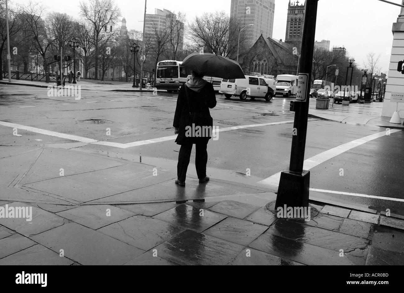 Homme avec parasol sur coin de rue pendant la tempête de pluie Banque D'Images