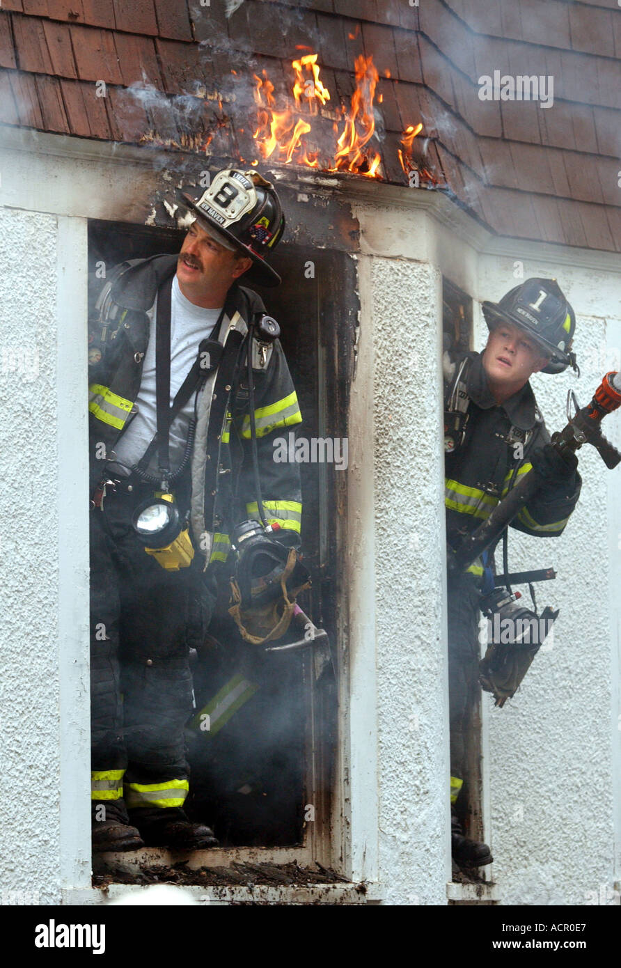 Pompiers Pompiers à la recherche d'un feu car il brûle au-dessus d'eux au cours d'une chambre d'urgence-incendie Banque D'Images