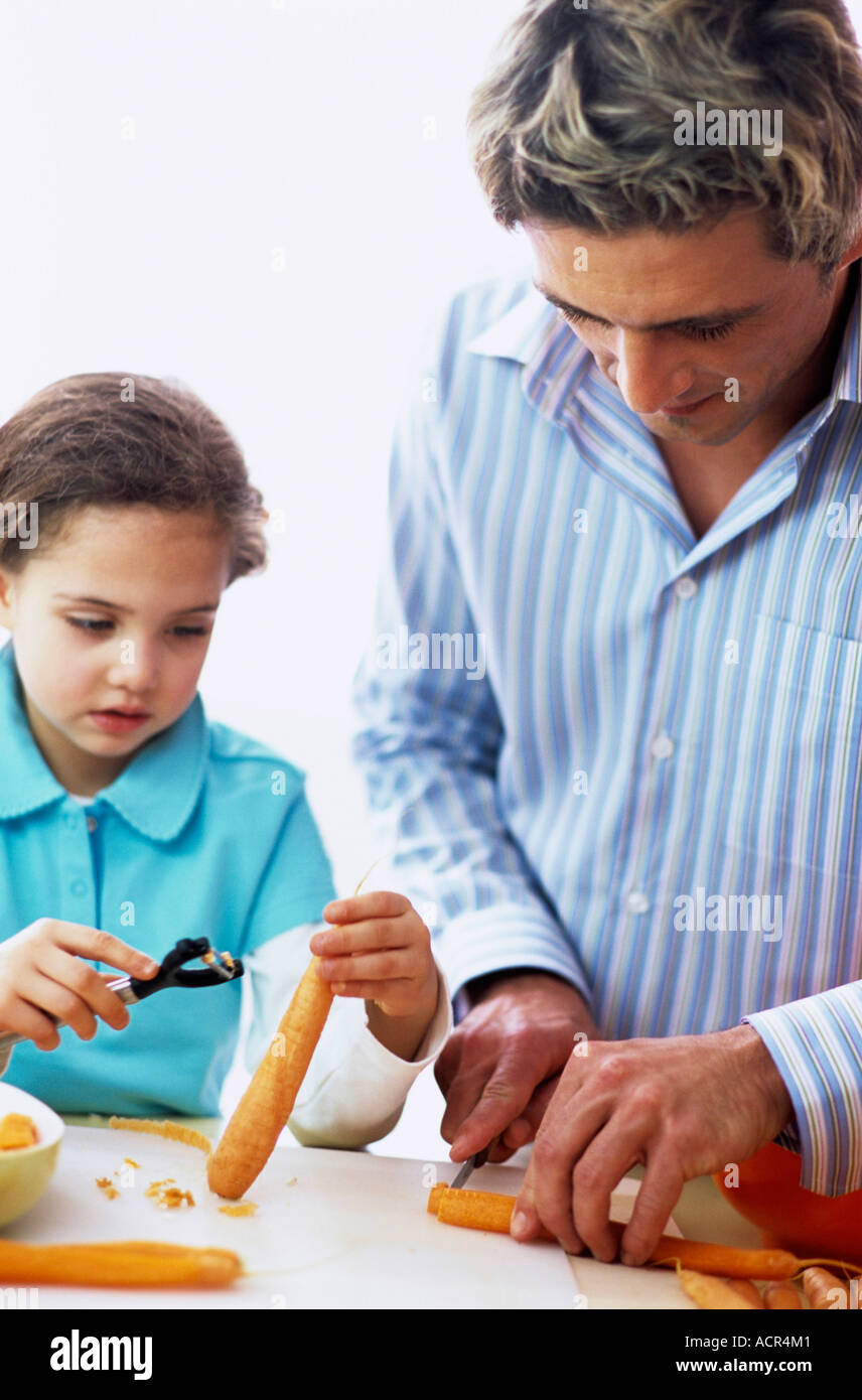 Père et fille à peler et couper les carottes en cuisine Banque D'Images