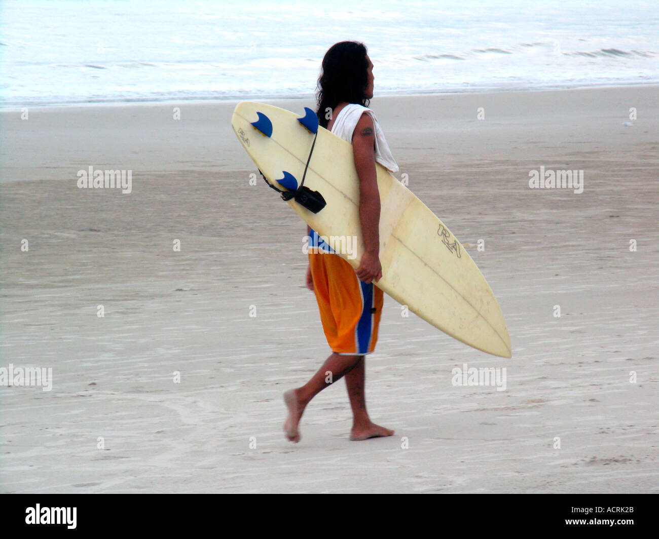 Surfer avec de longs cheveux et conseil en vertu de l'arm Pantai Cenang Beach l'île de Pulau Langkawi Malaisie Banque D'Images