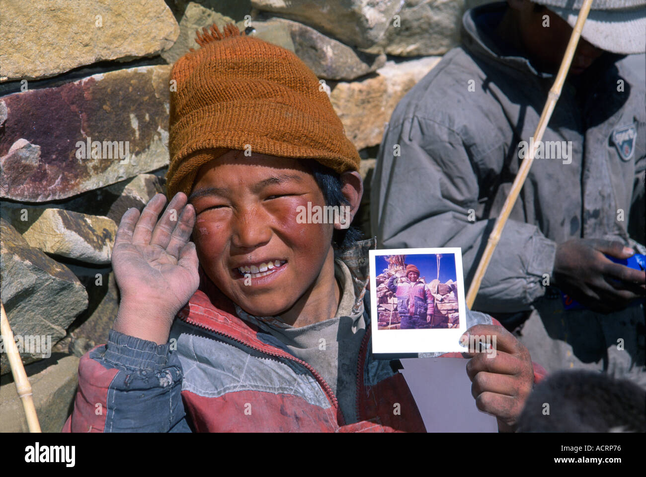 Un garçon tibétain affiche fièrement son seul et unique photographie un Polaroid prises par le photographe Jake Norton Banque D'Images