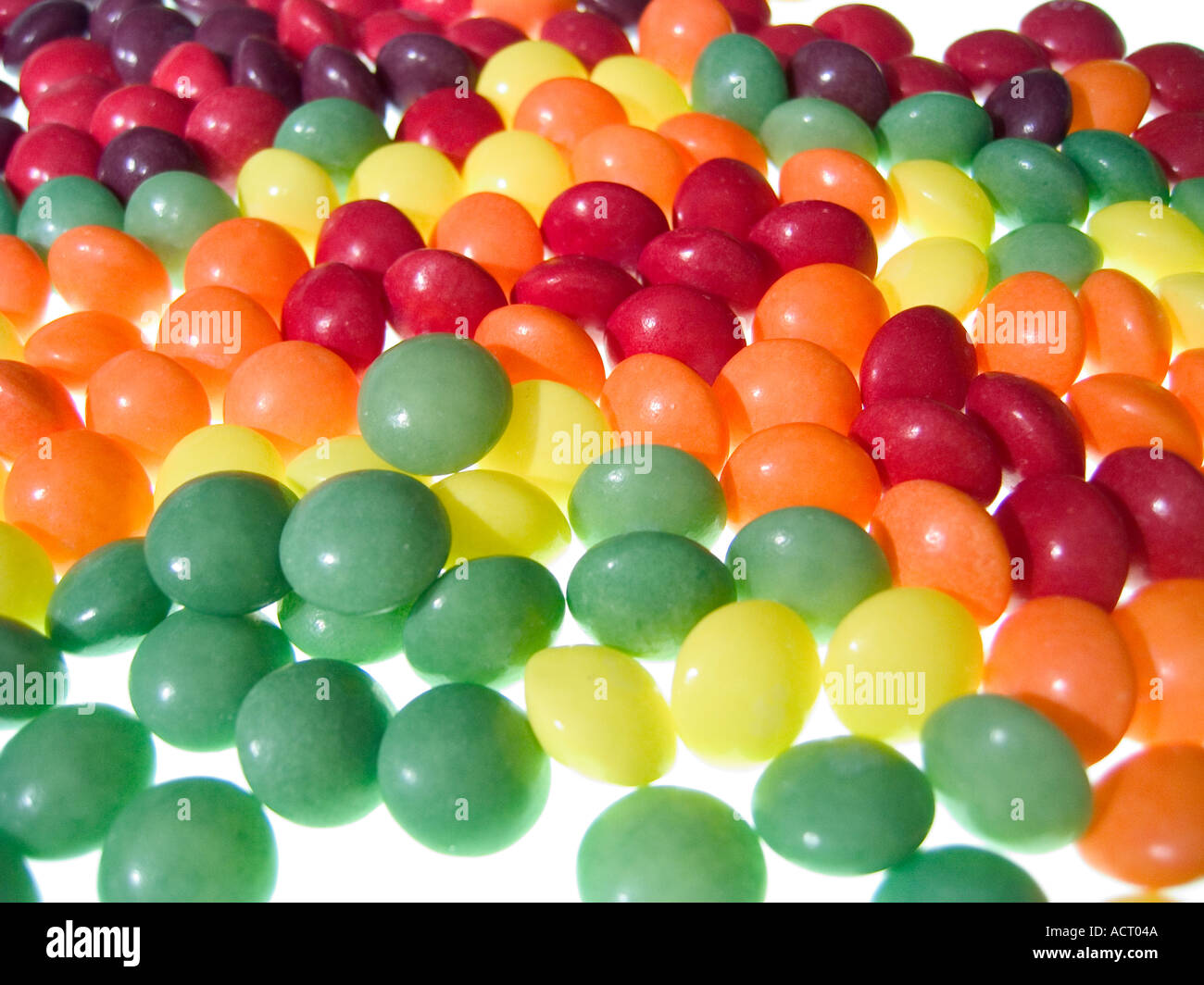 Vert rouge jaune et orange fruit rond bonbons éparpillés sur un modèle aléatoire Banque D'Images