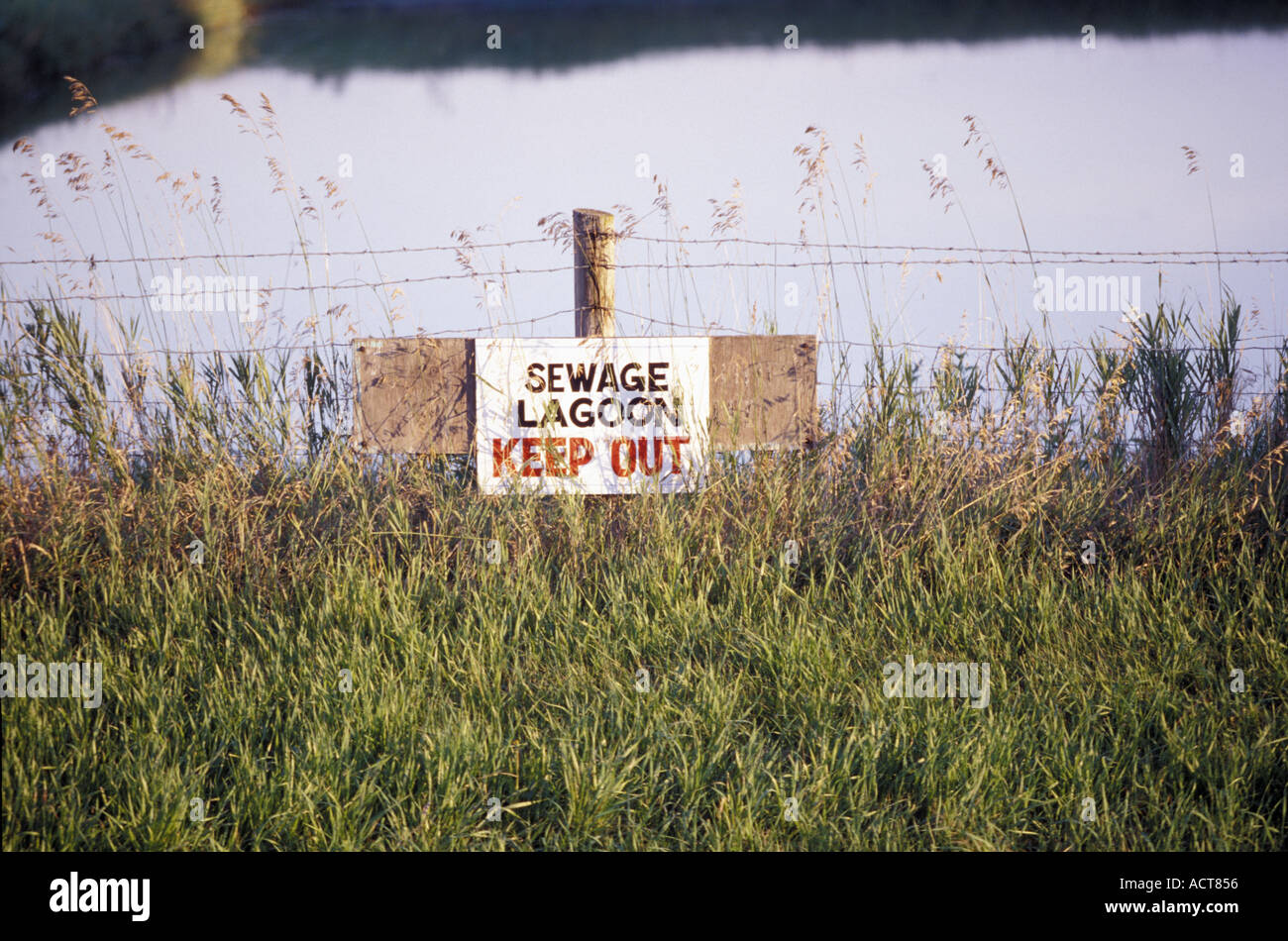 Garder hors des eaux usées de signer sur clôture derrière l'herbe en face de pond Banque D'Images