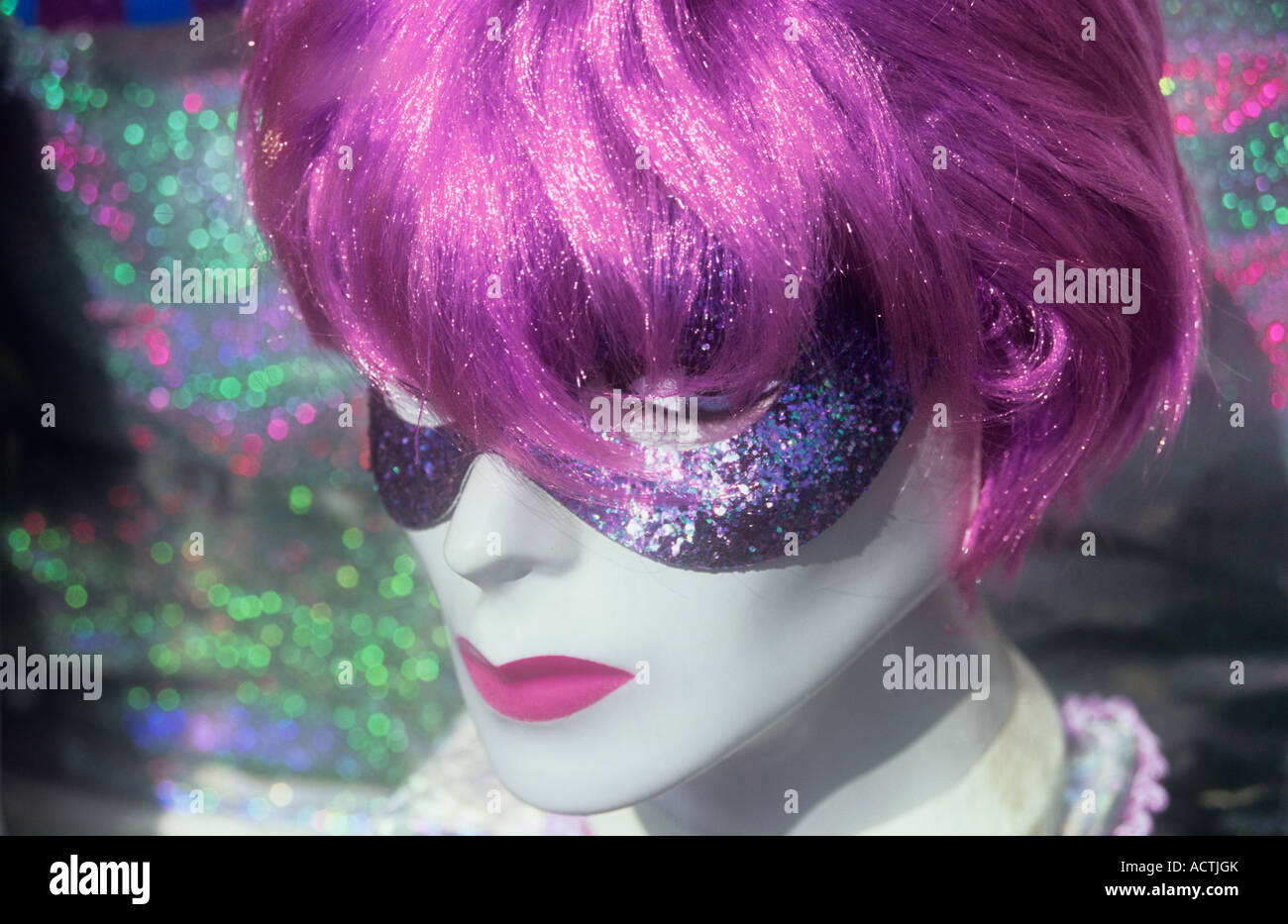Close up de vitrine tête artificielle portant sur-le-Haut de la perruque violette et de style vénitien masque yeux en face de chiffon spangly Banque D'Images Close up de vitrine tête artificielle portant sur-le-Haut de la perruque violette et de style vénitien masque yeux en face de chiffon spangly Banque D'Images