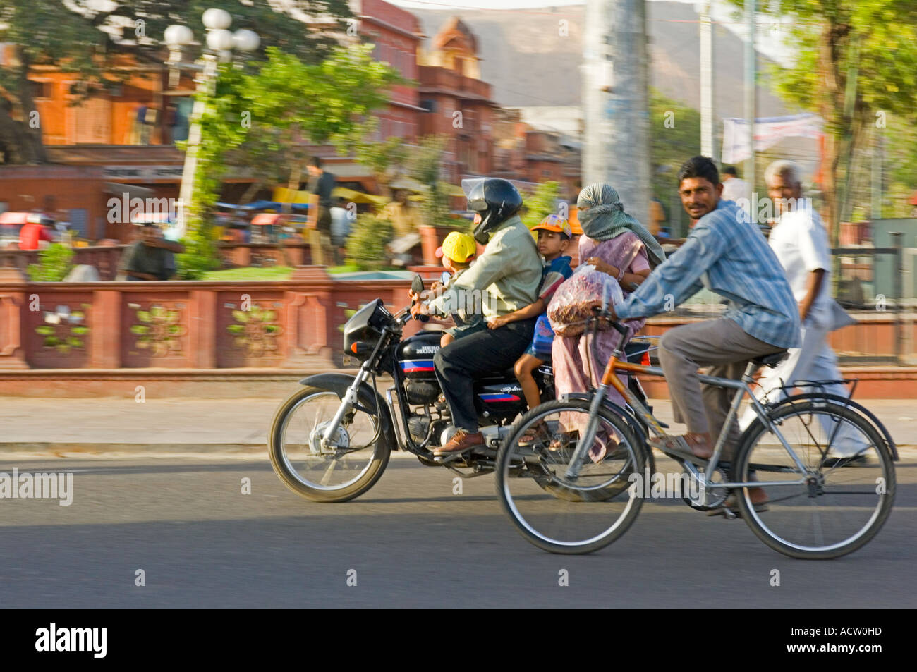 Une famille indienne de 4 sur une moto et l'homme à vélo dans une scène de rue typique à Jaipur avec le panoramique de flou. Banque D'Images