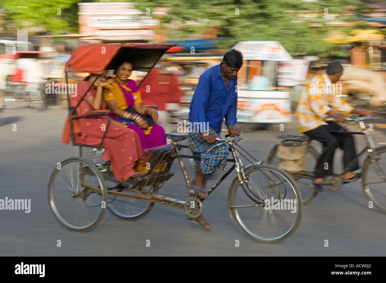 Deux femmes indiennes smiling attractive dans un cycle rickshaw dans une scène de rue à Jaipur avec le panoramique de flou. Banque D'Images