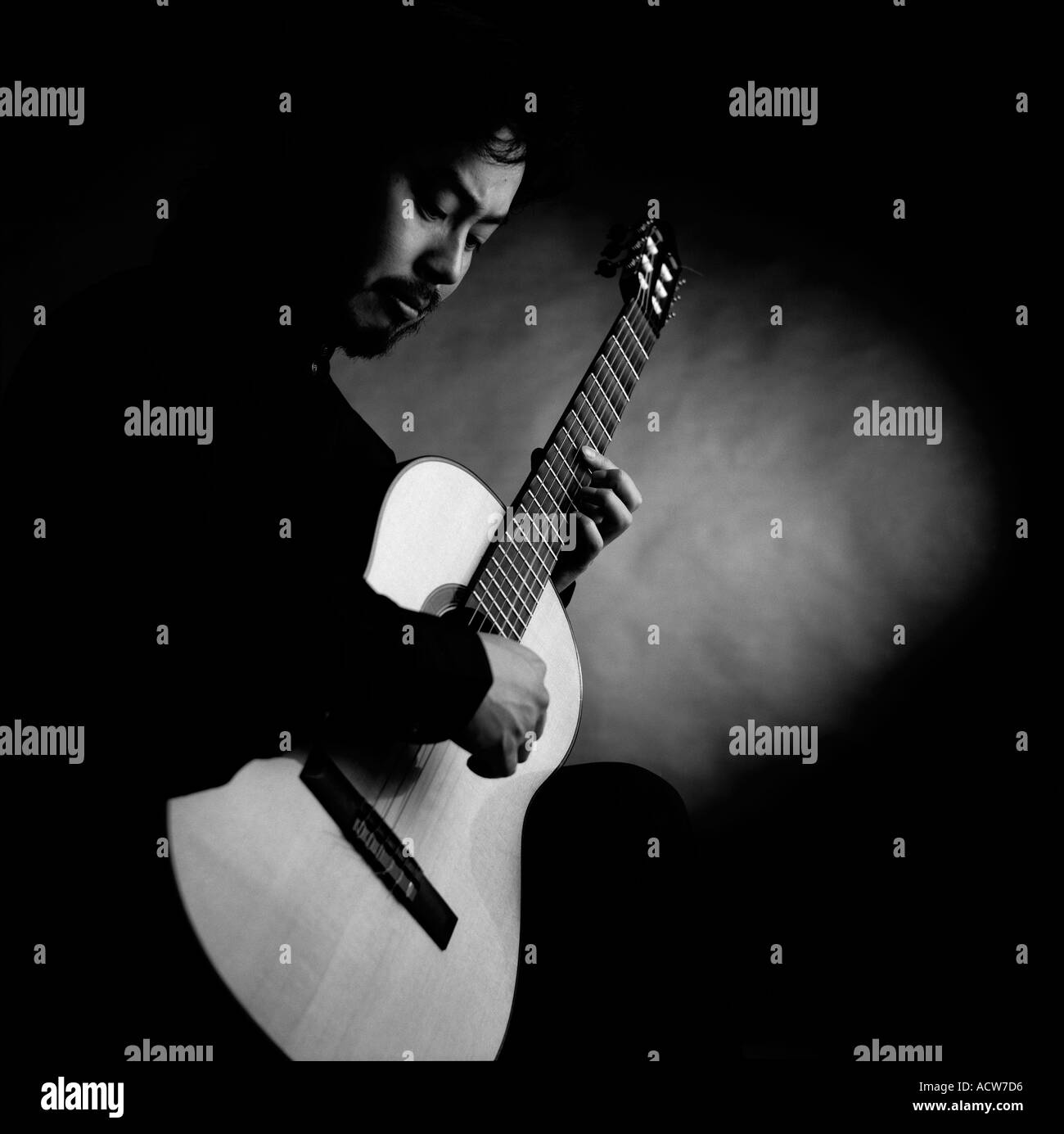 Portrait noir et blanc de guitariste classique concert Masa Ito dans studio fond noir Banque D'Images