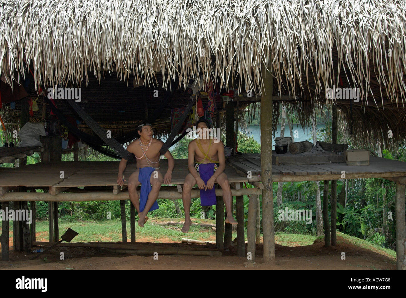 Deux hommes indiens indigènes assis sur une plate-forme surélevée dans une maison à l'Embera Indian Village près de Colon Panama Banque D'Images