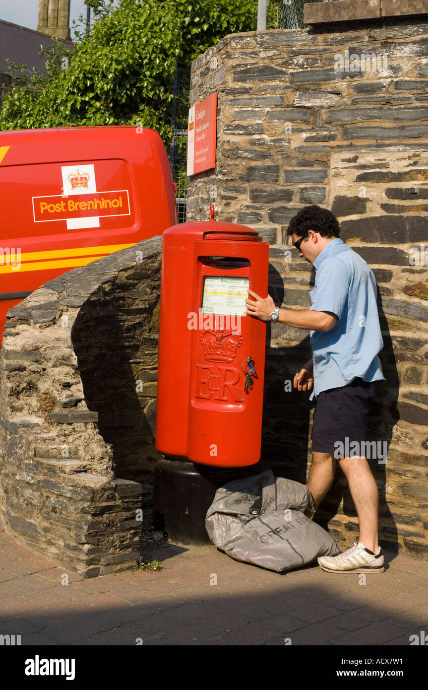Postman la collecte de vider le courrier d'une boîte à l'extérieur un dépôt postal Cardigan Wales (logo en gallois sur van derrière) Banque D'Images