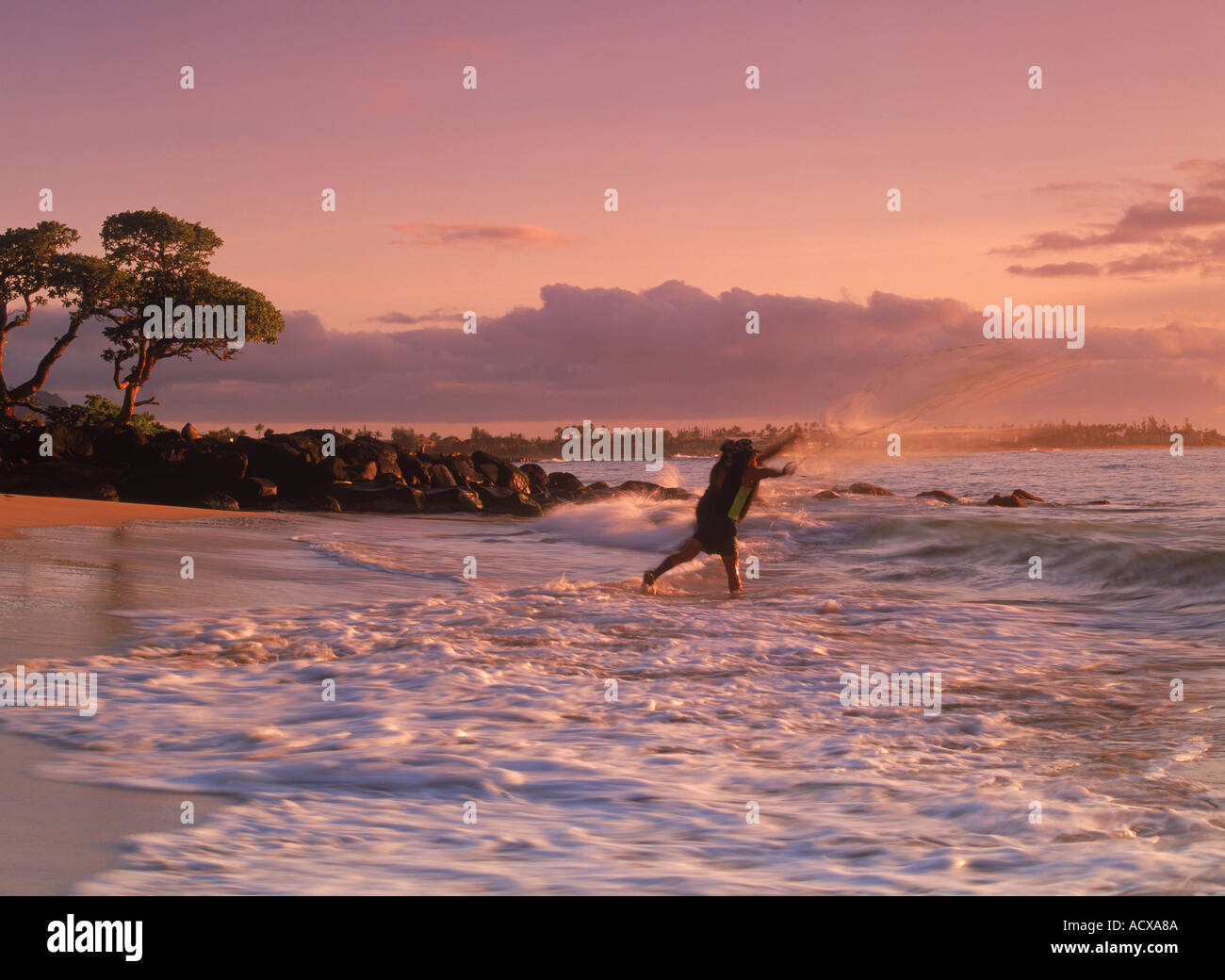 Fisherman casting en net surf shore sur l'île de Kauai au lever du soleil Banque D'Images