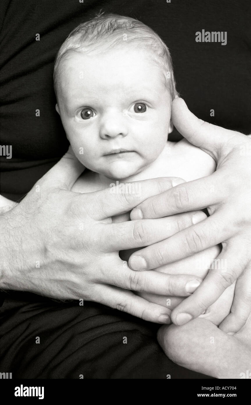 Le noir et blanc portrait de bébé nouveau-né dans les mains de son père Banque D'Images