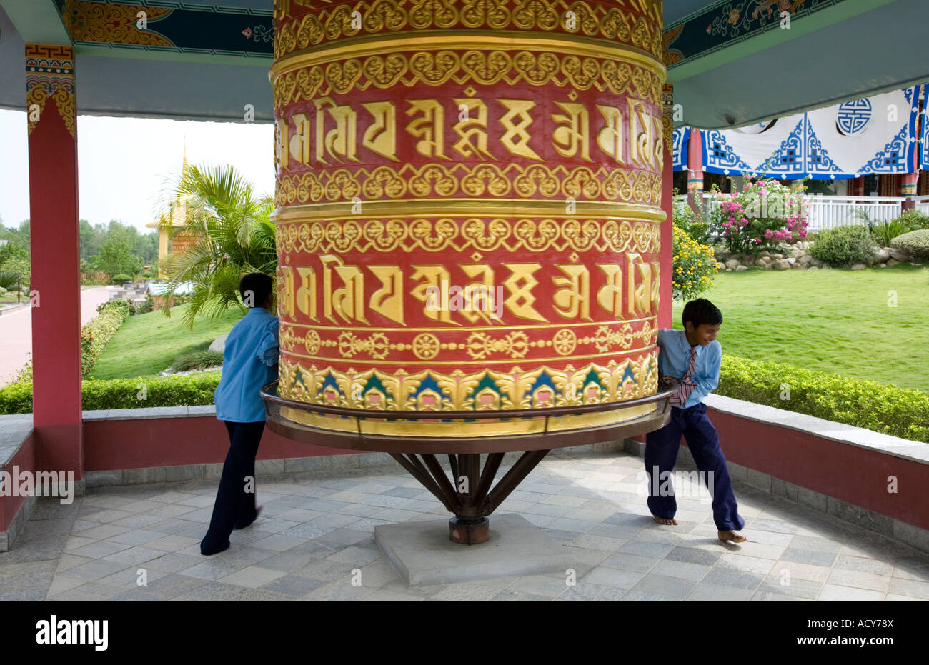 Les enfants la rotation d'un grand moulin à prières. Monastère bouddhiste allemand. Lumbini. Le Népal Banque D'Images