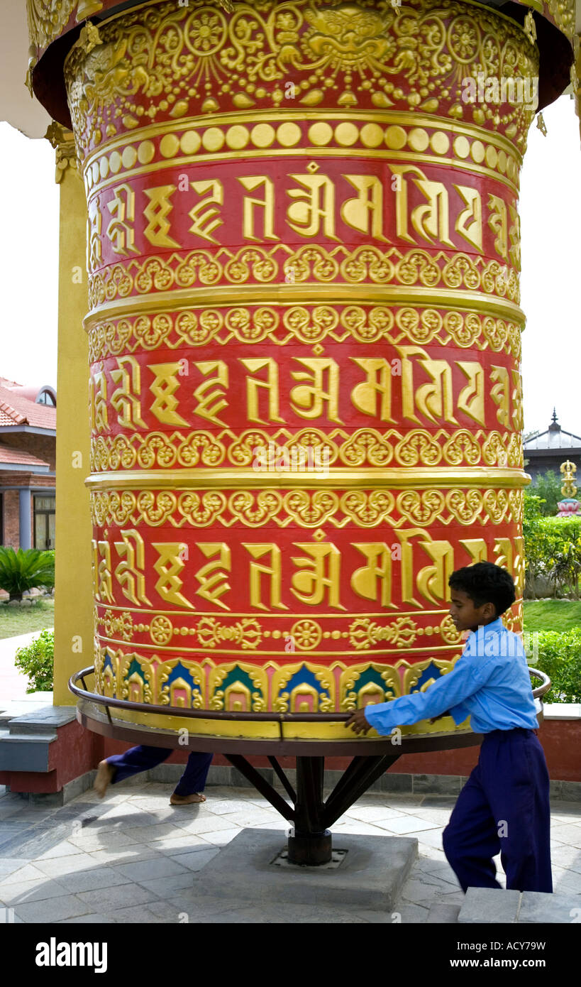 Boy spinning un grand moulin à prières. Monastère bouddhiste allemand. Lumbini. Le Népal Banque D'Images