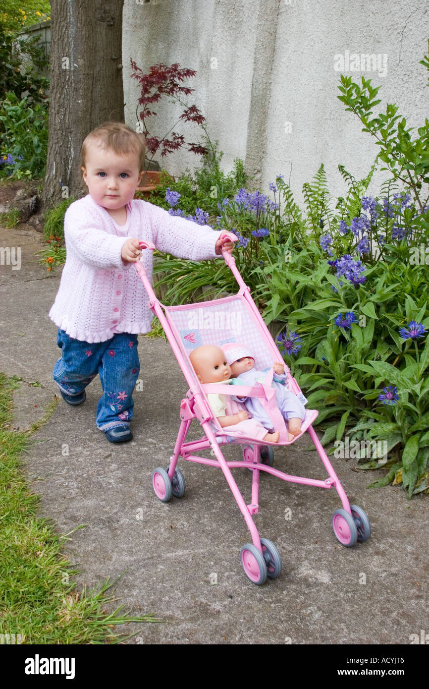Petite fille poussant une poupée autour du jardin dans une poussette buggy  Photo Stock - Alamy