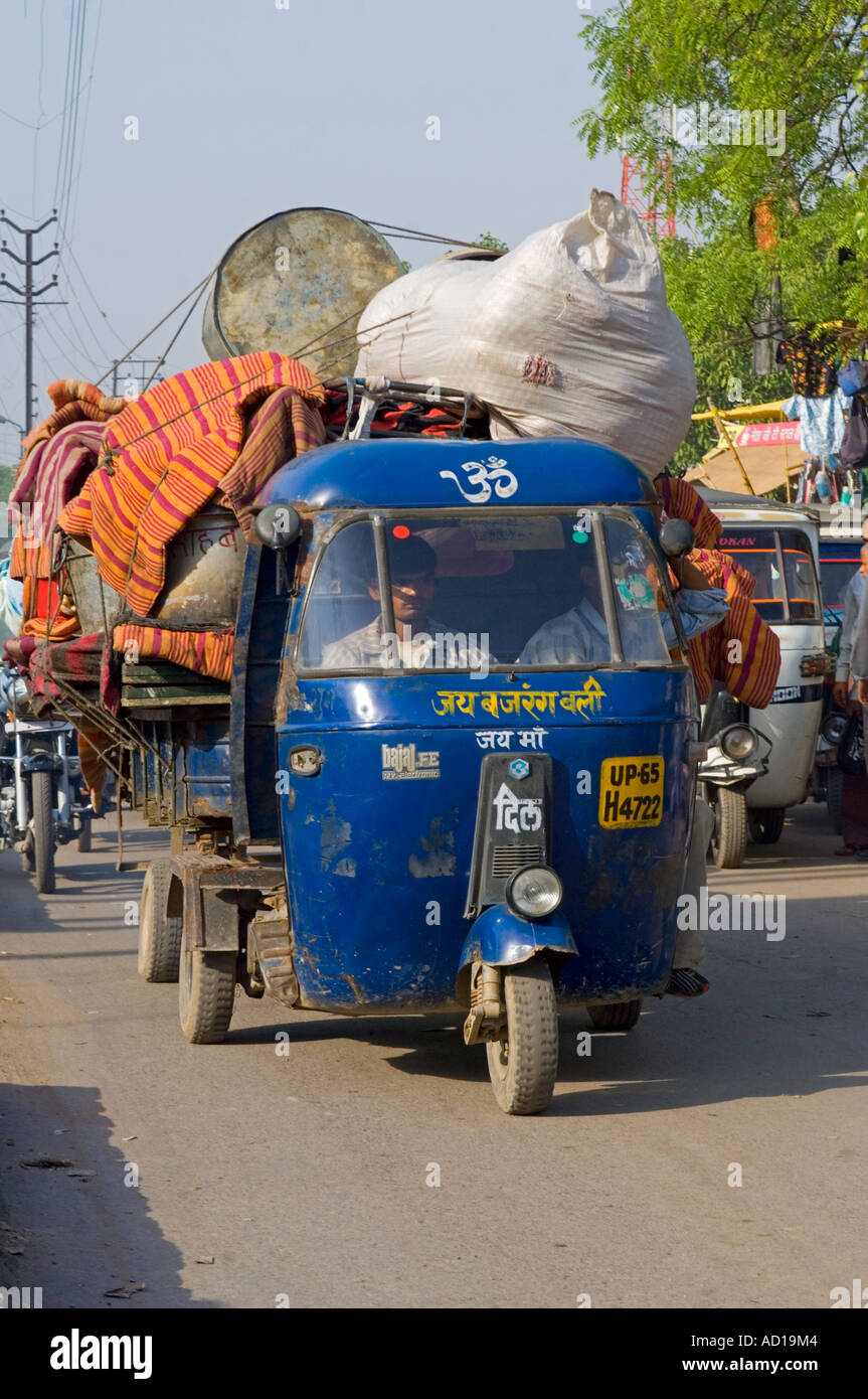 Une scène de rue à Varanasi avec un auto rickshaw (tuk tuk) et la remorque complètement surchargé avec des tas d'effets personnels. Banque D'Images