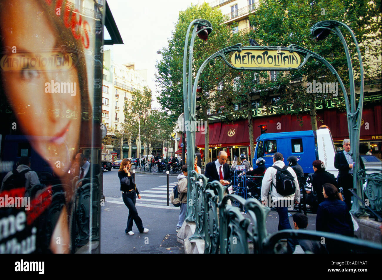 Femme parlant sur un téléphone en face d'une grande affiche publicitaire et l'Art Nouveau au métro Place de Clichy Paris, France Banque D'Images