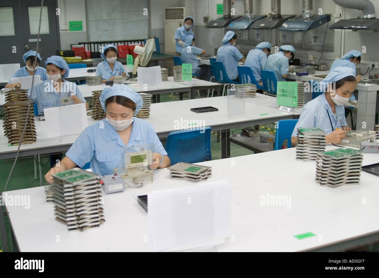 Les travailleurs de l'usine de haute technologie chinois travaillant à la main avec le montage des composants des cartes d'affichage LCD Banque D'Images