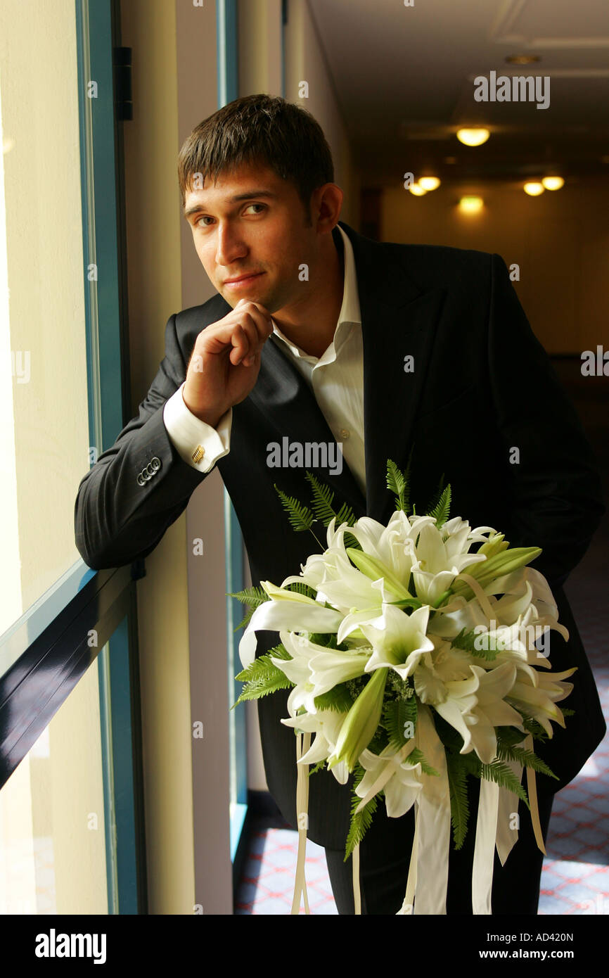 Un portrait d'un groom vu ici sur son mariage dans un costume traditionnel matin tenant un bouquet de fleurs. Banque D'Images