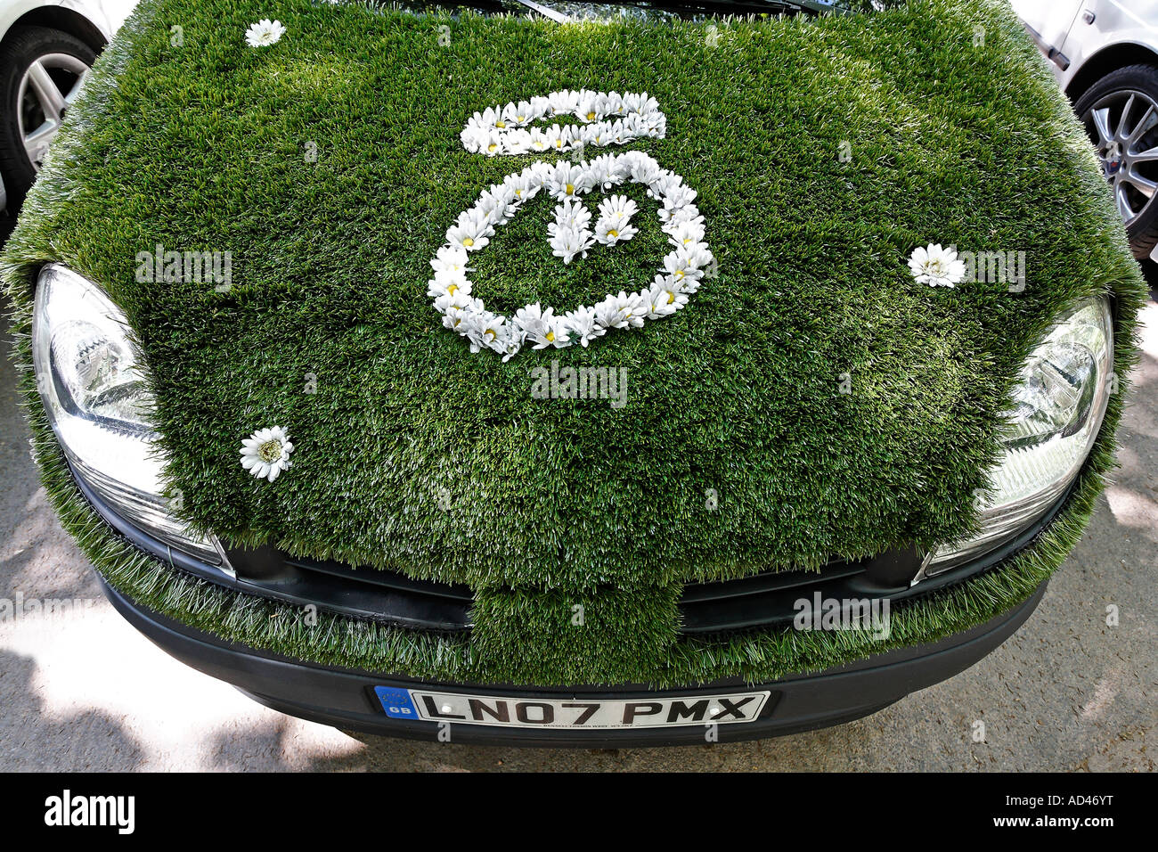 Drôle voiture respectueuse de l'environnement artificiel recouvert de lane, smiley avec halo fait de fleurs, Allemagne Banque D'Images