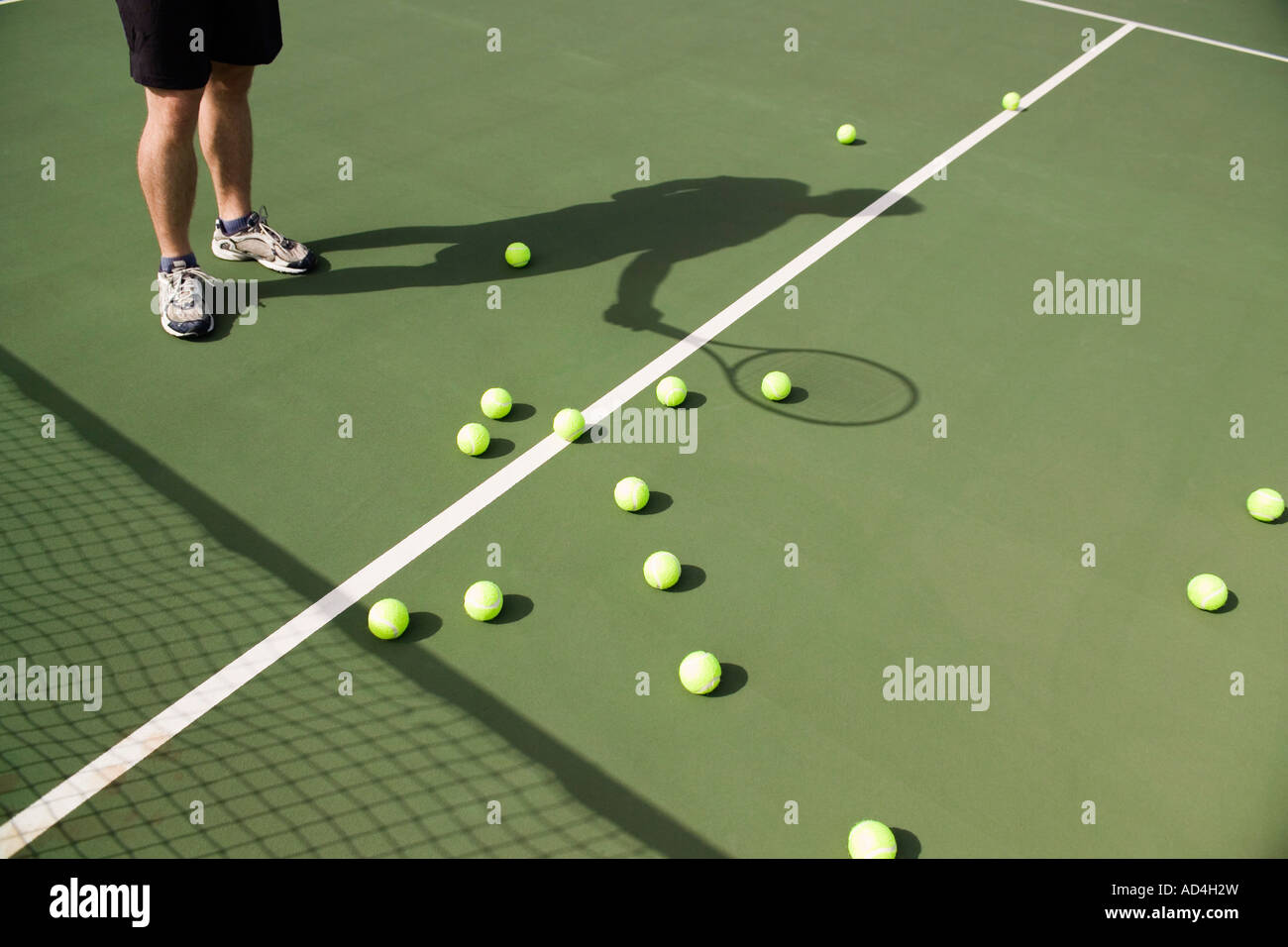 La section basse d'un joueur de tennis avec balles éparpillées sur la cour Banque D'Images