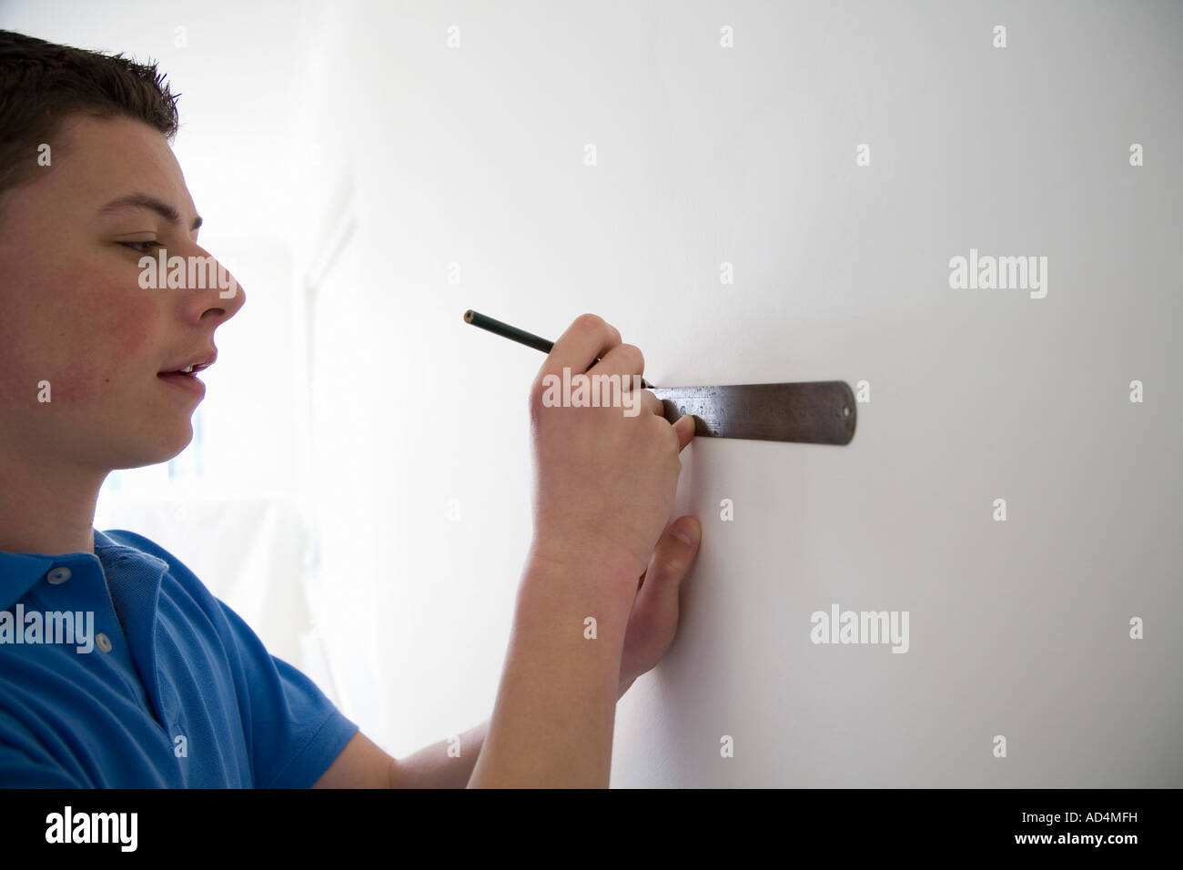 Teenage boy mesurant un mur Banque D'Images