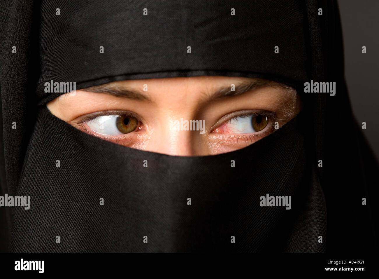 Close up head shot d'une femme musulmane dans un hijab noir avec les yeux à la recherche sur le côté Banque D'Images