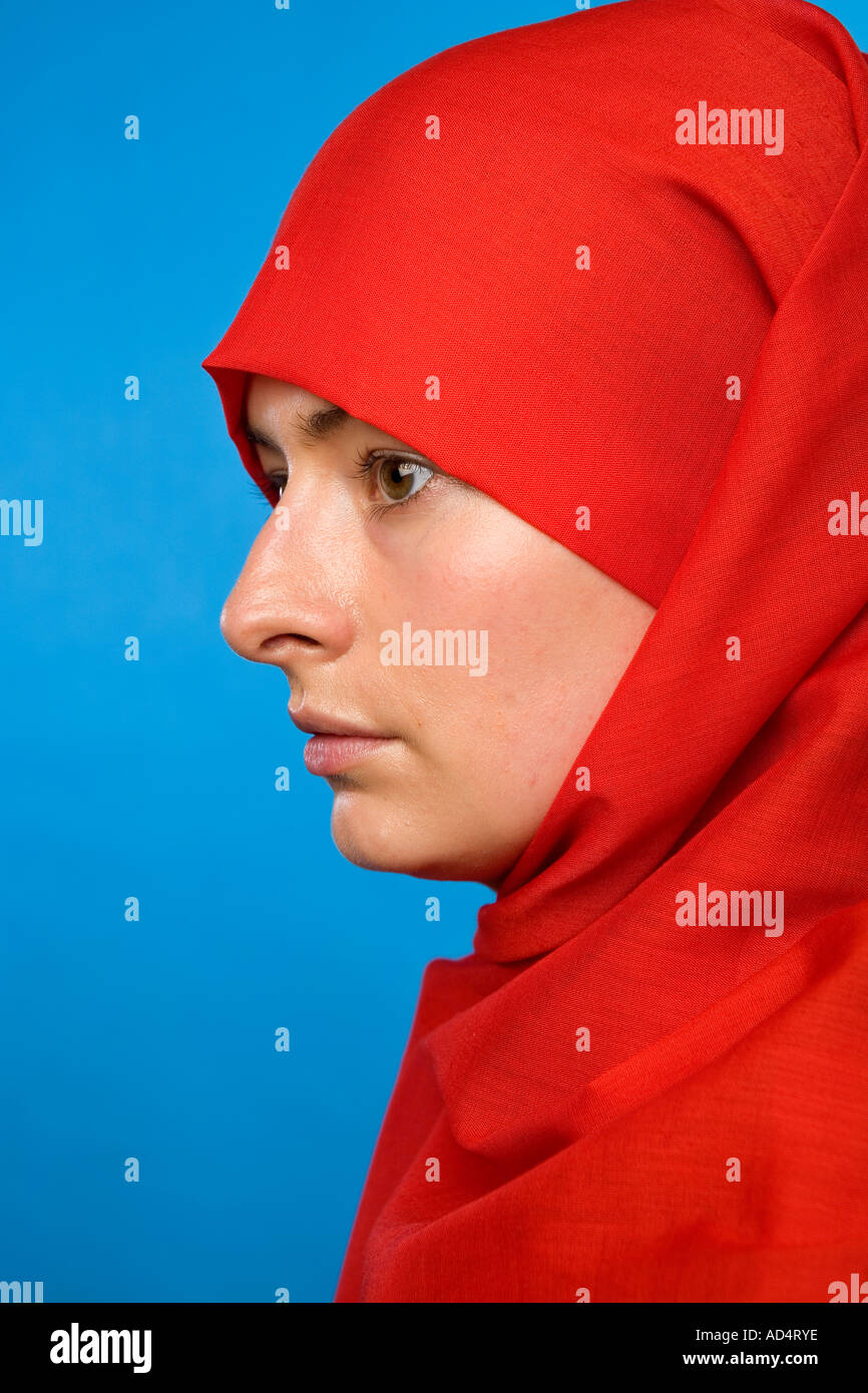 Close up profile head shot d'une femme musulmane dans un hijab rouge avec les yeux regardant droit devant Banque D'Images