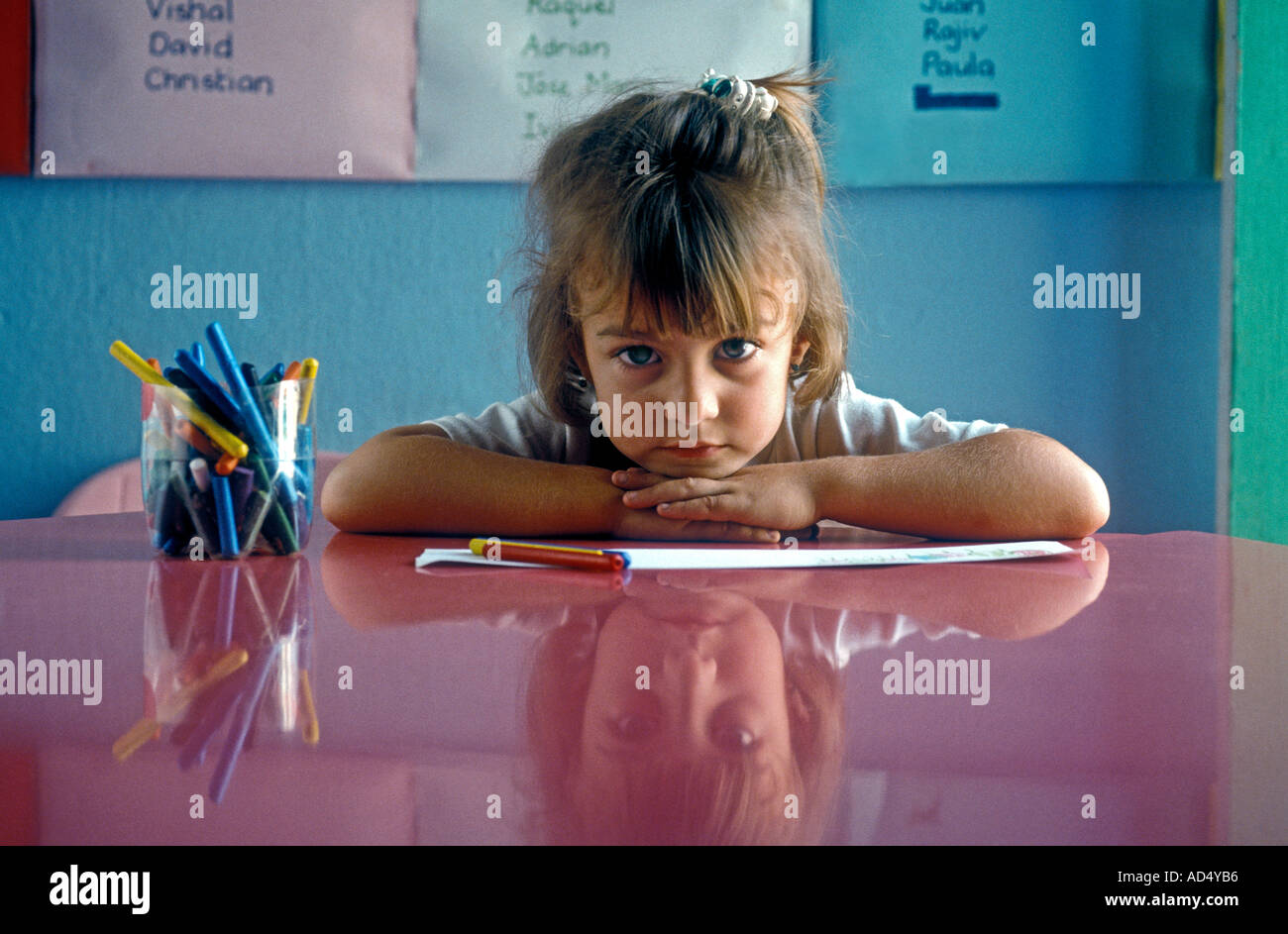 La Hispanic lycéenne en maternelle l'accueil de 3 à 4 ans séance pensive, à l'école de classe à un bureau menton sur les mains à la réflexion Banque D'Images