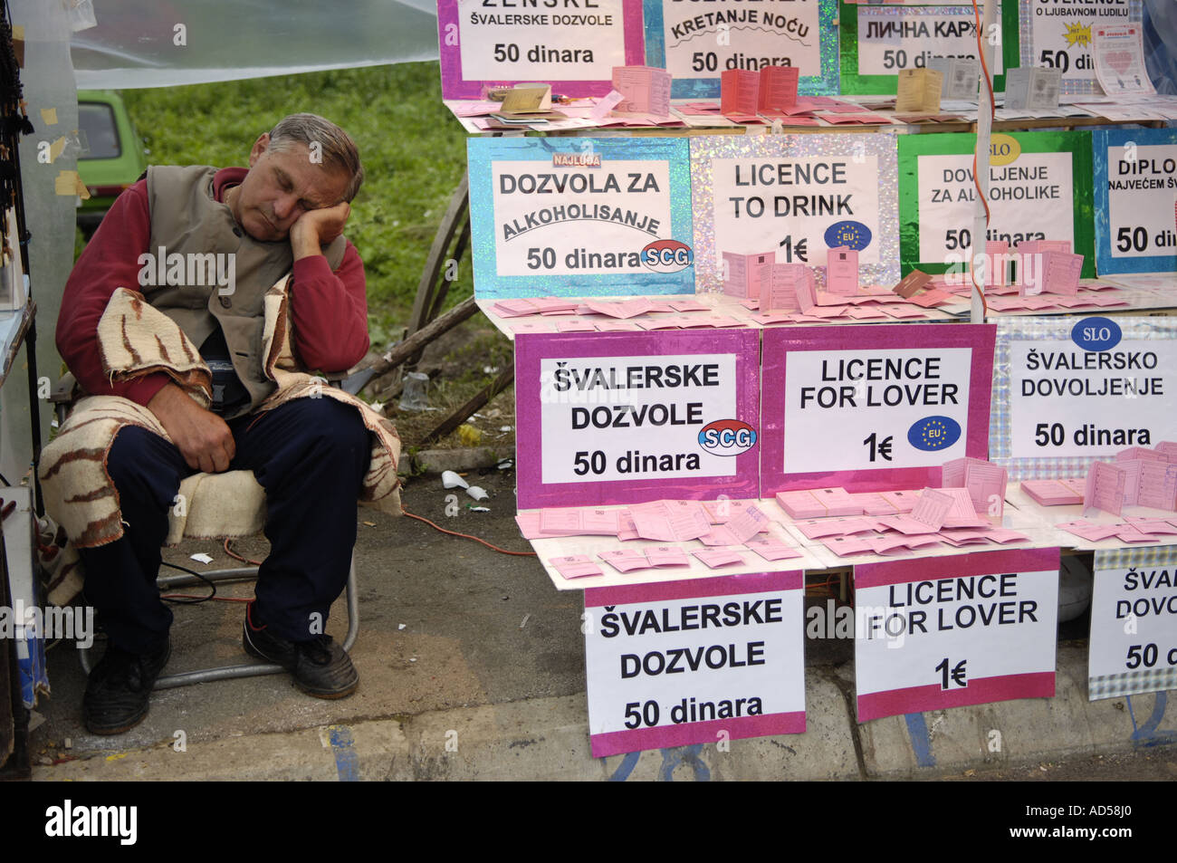 Fanfares balkaniques Guca Festival de musique / Serbie 2005, l'homme dort à côté de son stand de vente avec des faux documents Banque D'Images