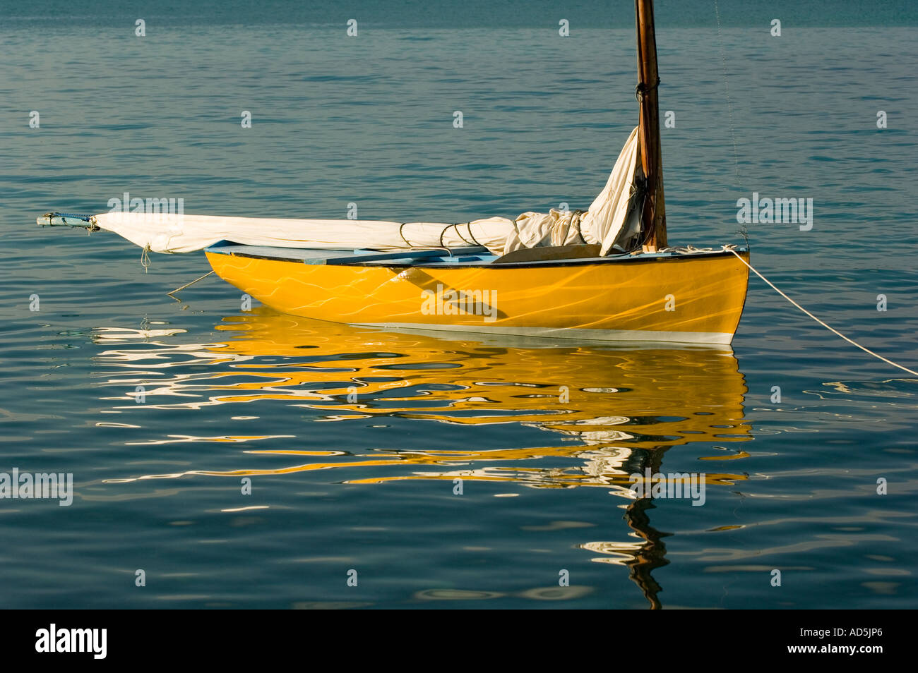 Une plus grande BAHAMA George Town Exuma Sloop voilier en bois coloré reflétant dans le vert émeraude Elizabeth Bay Banque D'Images
