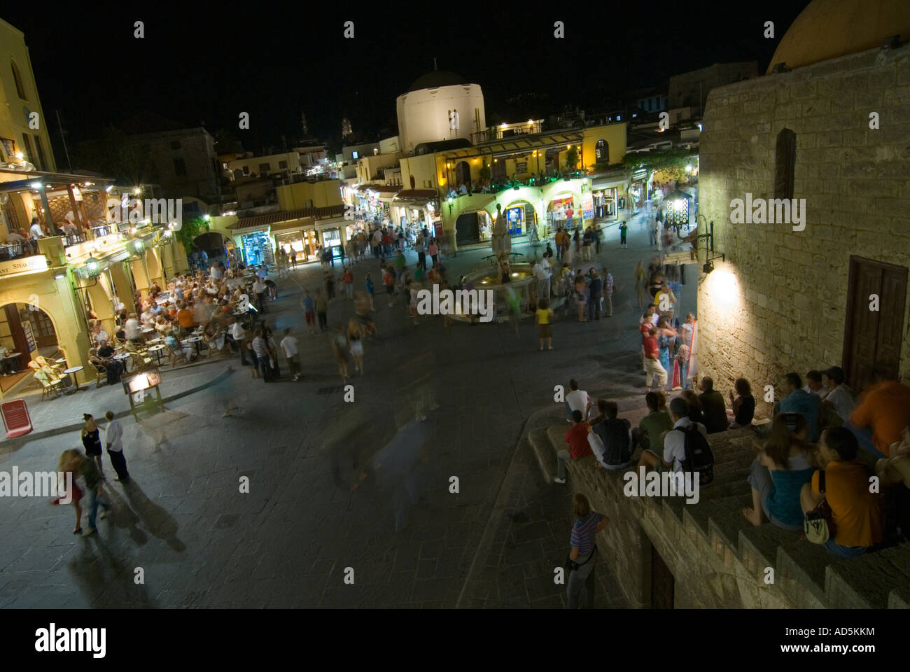 Grand angle élevé horizontale de gens assis sur les marches dans le populaire Ippokratous Square de la vieille ville de Rhodes dans la nuit. Banque D'Images