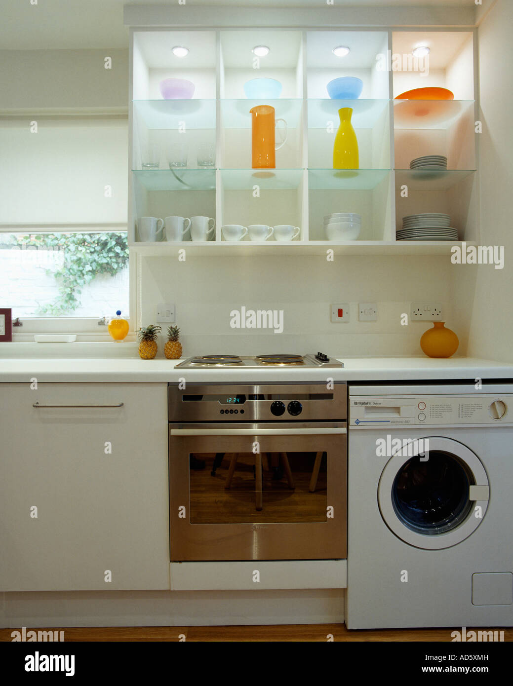 Chrome et blanc four machine à laver en dessous des étagères en verre  éclairé avec des vases de cuisine moderne blanc Photo Stock - Alamy