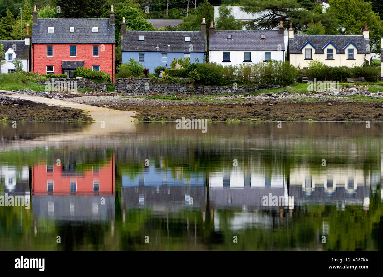 Maisons peintes de couleur reflète dans l'eau à côté du château Eilean Donan en Ecosse Banque D'Images