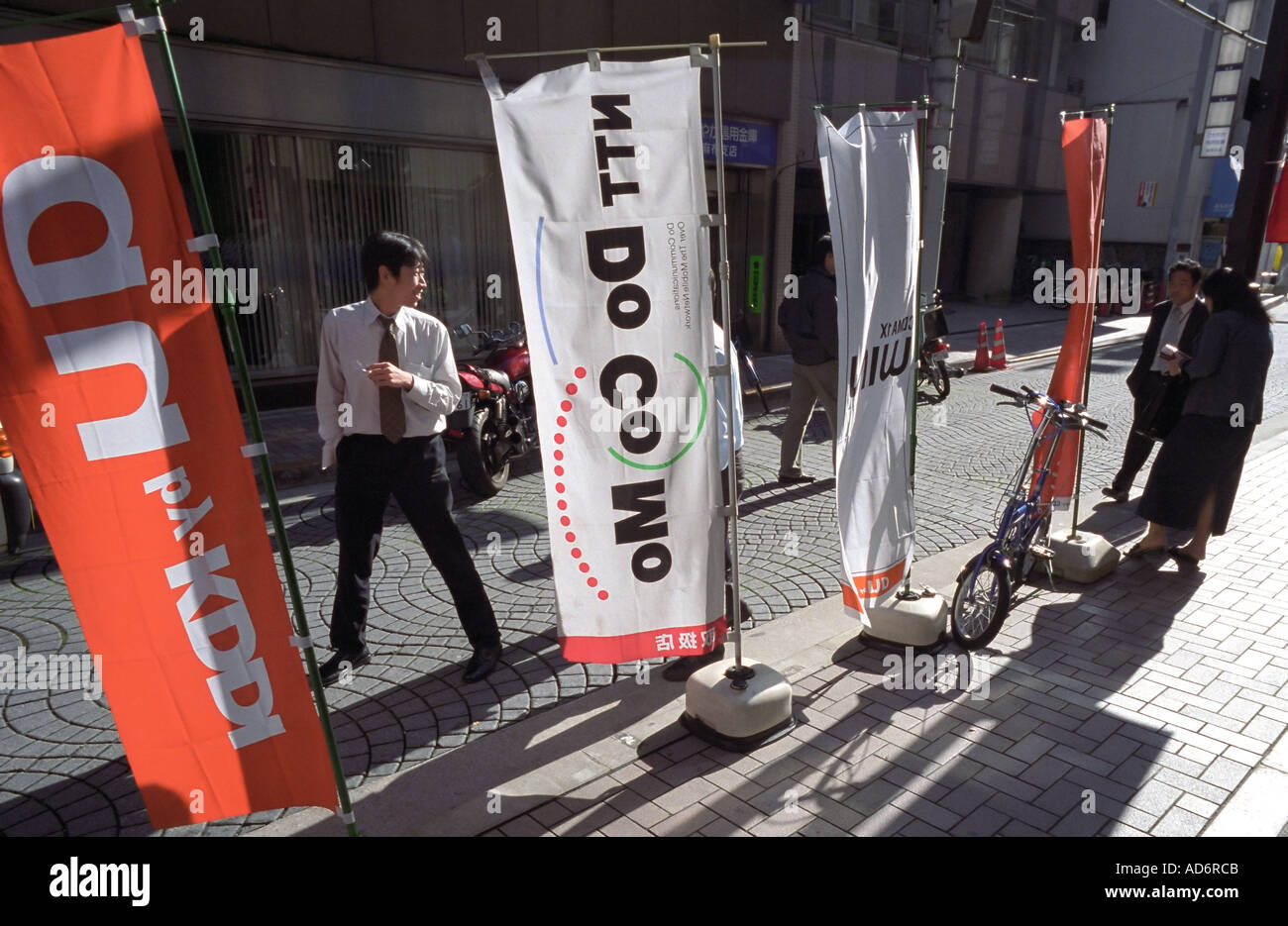 L'affichage de drapeaux et publicité pour un téléphone et communications company dans une rue de Tokyo Banque D'Images