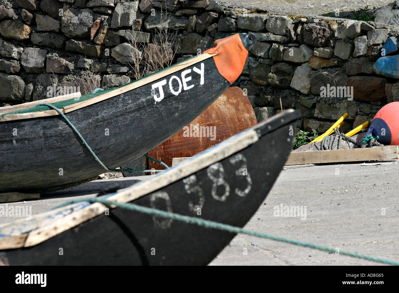 Deux currachs nez pointu de plaisance navigant un nommé Joey attaché à un mur en pierre la mer attendent la marée pour flotter entre eux Banque D'Images