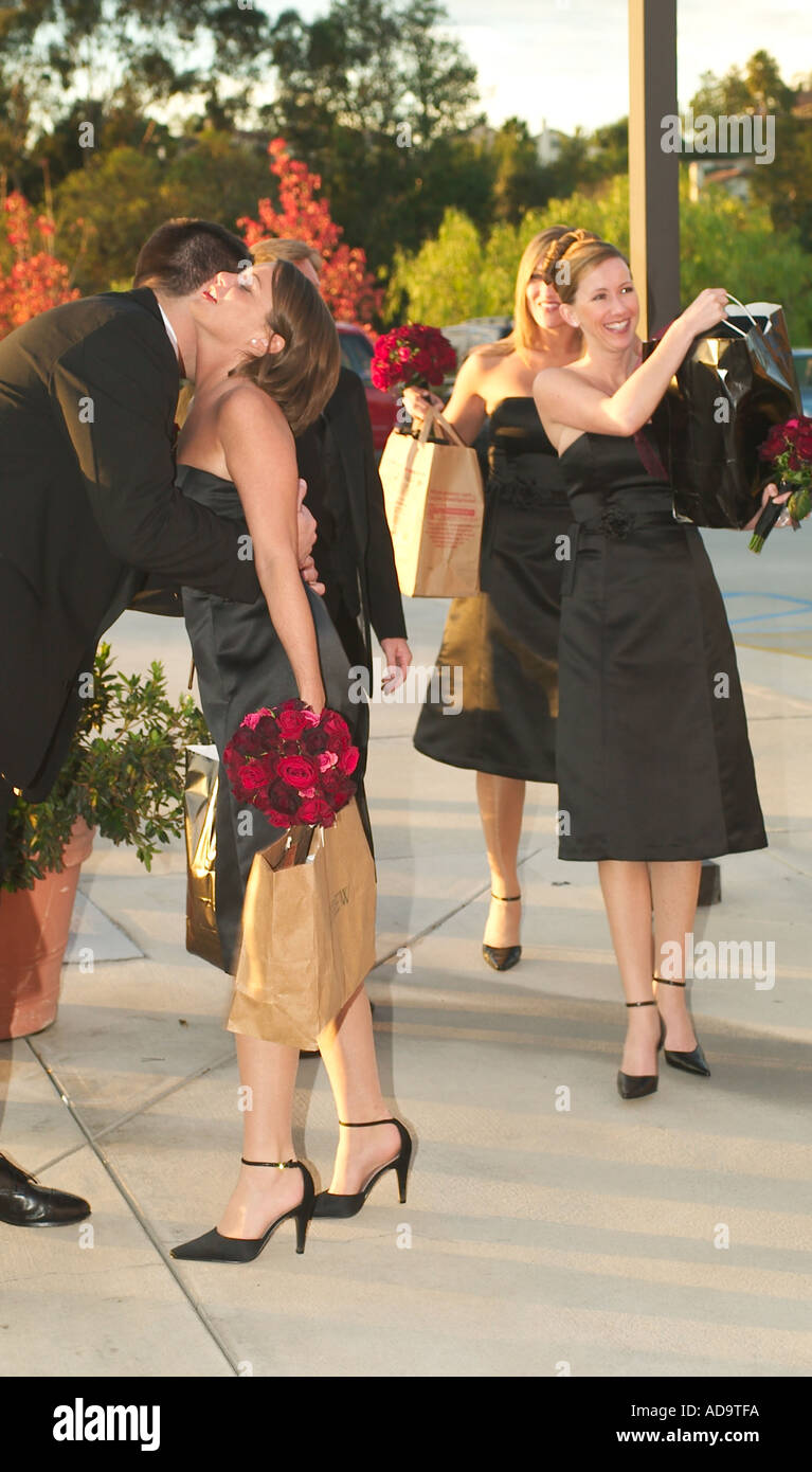Une demoiselle d'arrivée reçoit un baiser d'une groomsman comme elle et les autres demoiselles d'arriver pour un mariage catholique dans Lag Banque D'Images
