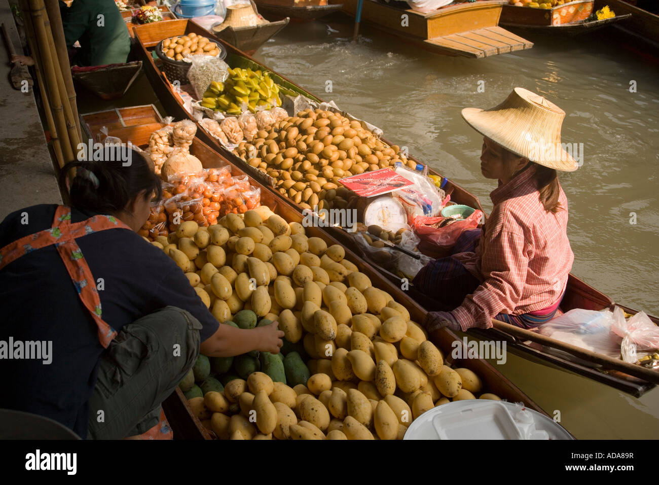 Femme choisissant fruits au marché flottant Damnoen Saduak près de Bangkok Thaïlande Ratchaburi Banque D'Images