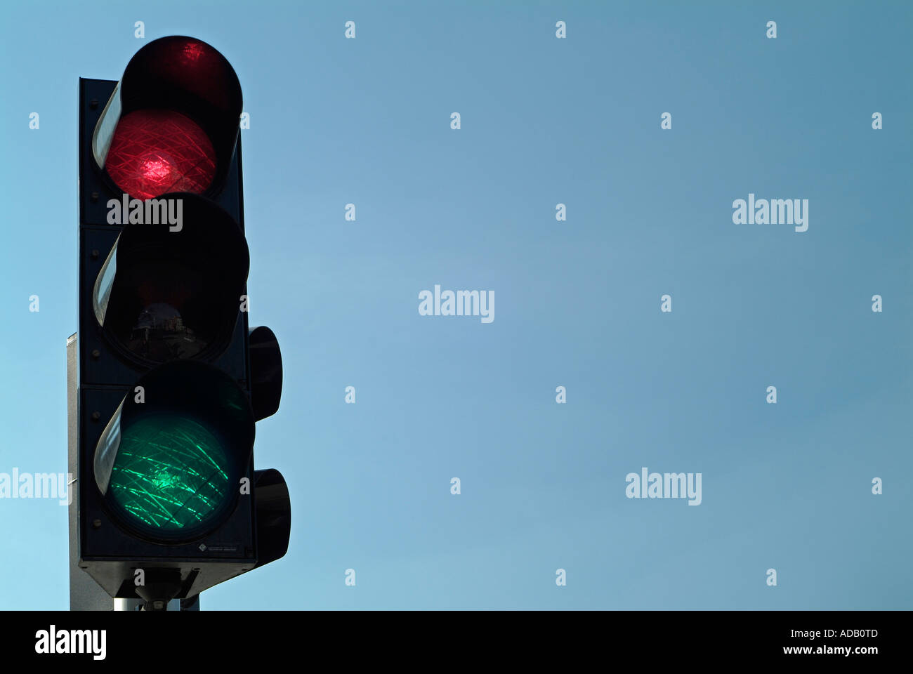 Signal de feux de circulation sur le rouge et vert contre un ciel bleu Banque D'Images