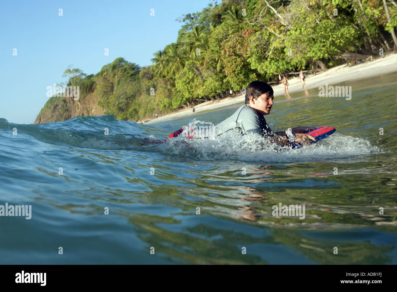 Boy riding a wave sur une planche de surf à la plage Banque D'Images