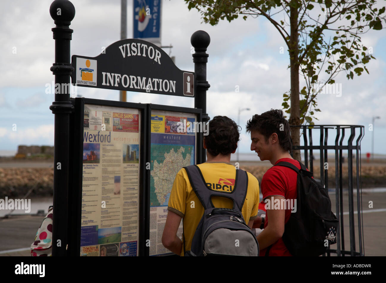 Deux jeunes hommes de touristes espagnols avec des sacs d'oeil à l'information touristique à Wexford town Banque D'Images