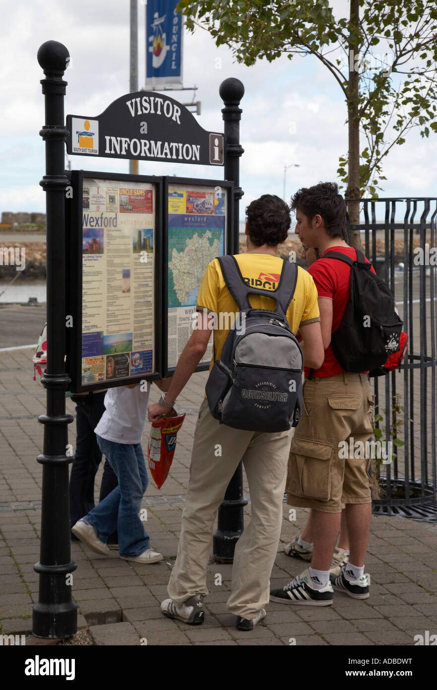 Deux jeunes hommes de touristes espagnols avec des sacs d'oeil à l'information touristique à Wexford town Banque D'Images